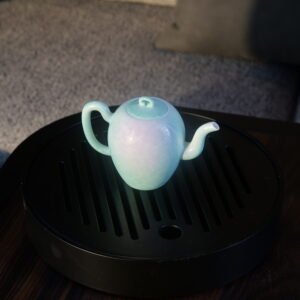 Spring glow gradient beauty shoulder teapot with hand-carved hundred flowers pattern placed on a black tea tray in living room setting