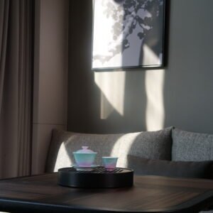 Wide-angle interior lifestyle view of the Spring Glow Gradient Elegant Charm Gaiwan and matching teacup on a dark wooden table in a brightly lit modern tea room with sunlight streaming in