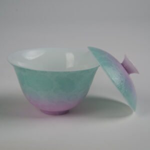 Side view of the Spring Glow Gradient Elegant Charm Gaiwan without saucer, with the lid leaning against the cup to reveal the white porcelain interior, soft pink and fresh green gradient glaze, and handcrafted Pa Hua floral pattern