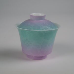 Side view of the Spring Glow Gradient Horseshoe Gaiwan without saucer, showing its lid and cup with soft pink-purple and green gradient glaze, horseshoe silhouette, and fine engraved Pa Hua daylily patterns