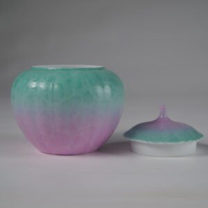 Front view of open spring glow gradient melon jar next to its porcelain lid