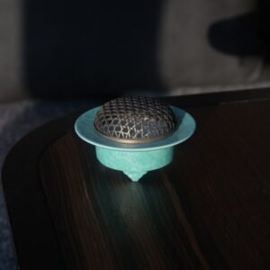 Angled view of turquoise ceramic incense burner on dark wooden table