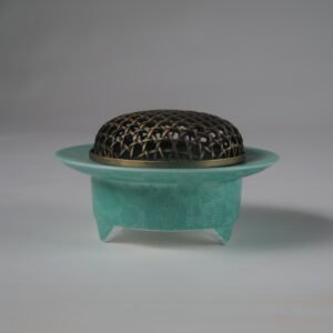 Side view of turquoise carved ceramic incense burner with copper mesh lid