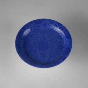 Top down view showing hundred flowers carved pattern on ultramarine porcelain plate