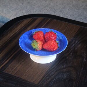Ultramarine porcelain pedestal plate holding fresh strawberries