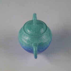 High angle rear perspective view showing the handle and lid knob of a verdant blue Pan's teapot