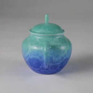 Eye-level rear view facing the handle of a verdant blue Pan's porcelain teapot