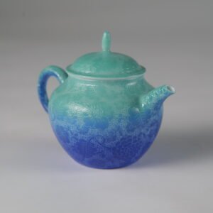 Eye-level side profile of verdant blue Pan's teapot featuring hand-carved hundred flowers Pa Hua pattern