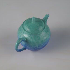 Side view of verdant blue porcelain Pan's teapot showcasing classic round body shape and hand-carved Pa Hua details