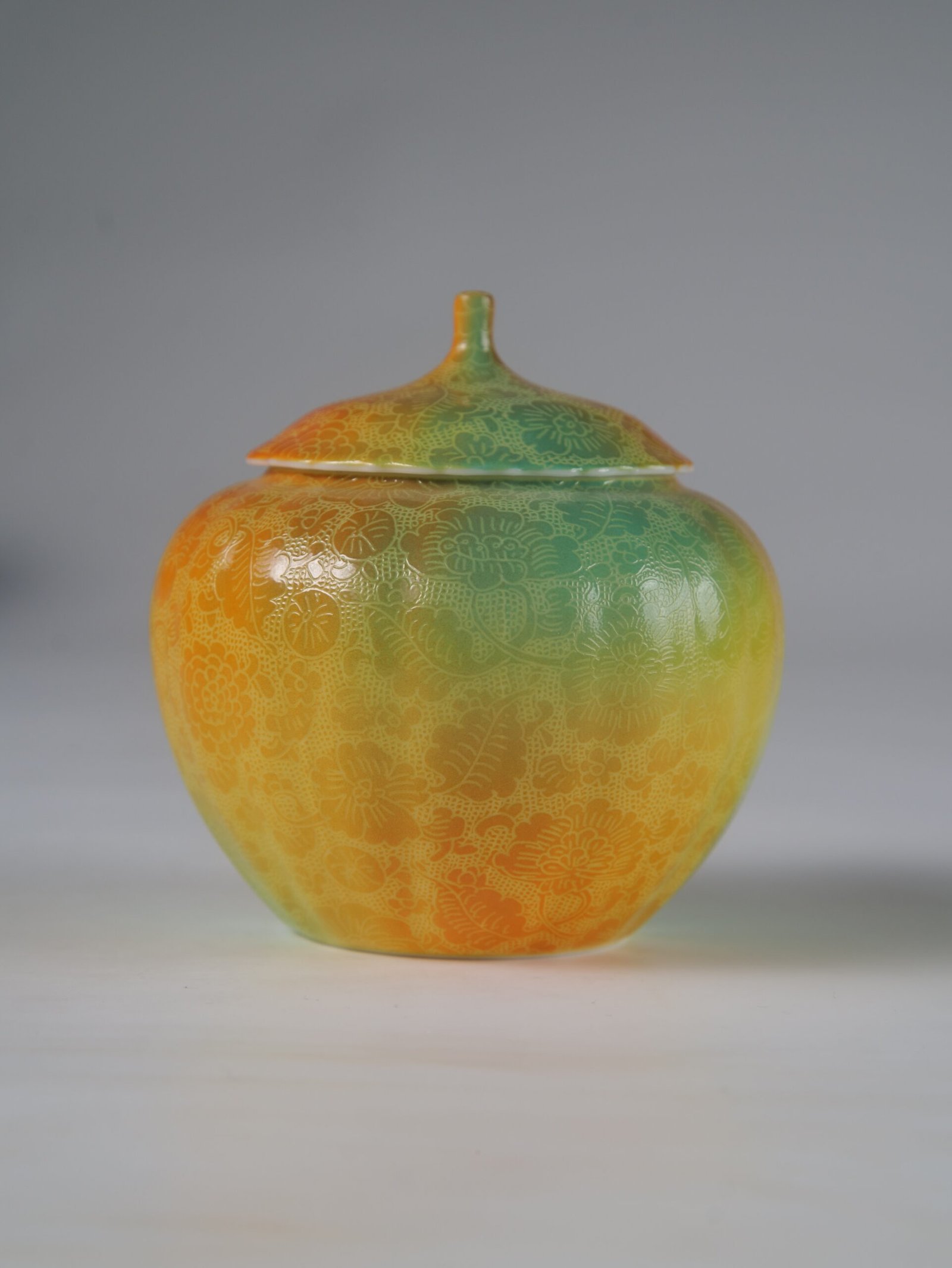 Verdant Clouds with Orange Hues Melon Jar - Front Profile Eye level front view of verdant clouds with orange hues melon-shaped jar with hundred flowers pattern