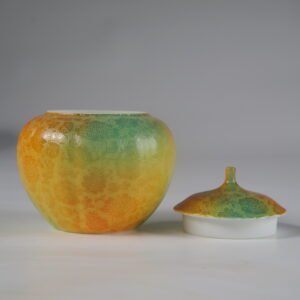 Front view of open verdant clouds with orange hues melon jar next to porcelain lid