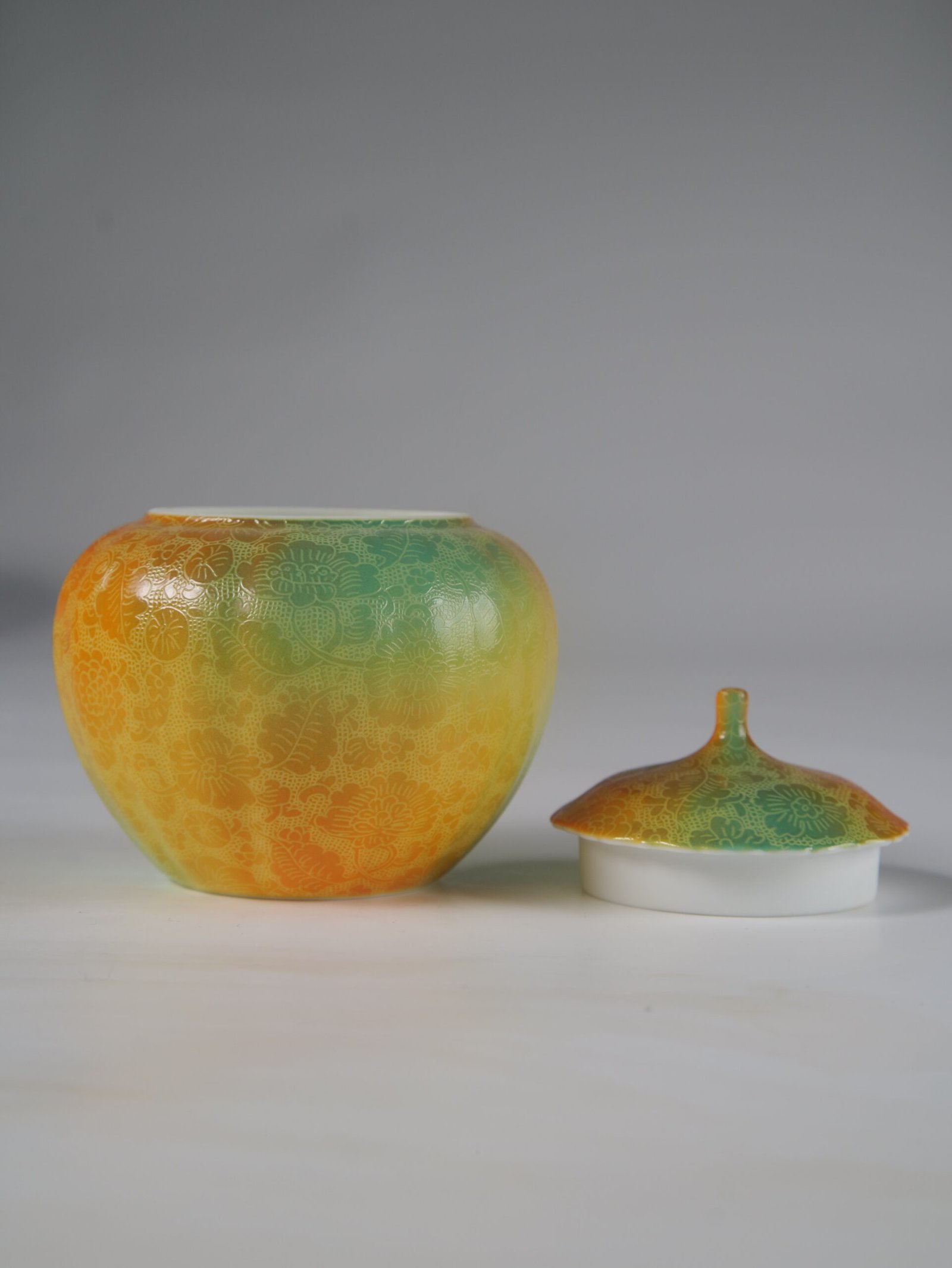 Verdant Clouds with Orange Hues Melon Jar – Open Lid View Front view of open verdant clouds with orange hues melon jar next to porcelain lid
