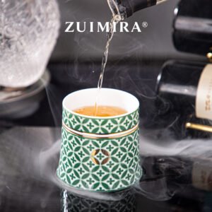 Pouring tea into the green rotatable ceramic cup on a reflective tabletop