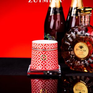 Red rotatable cup styled with brandy bottles on a dark table under warm light
